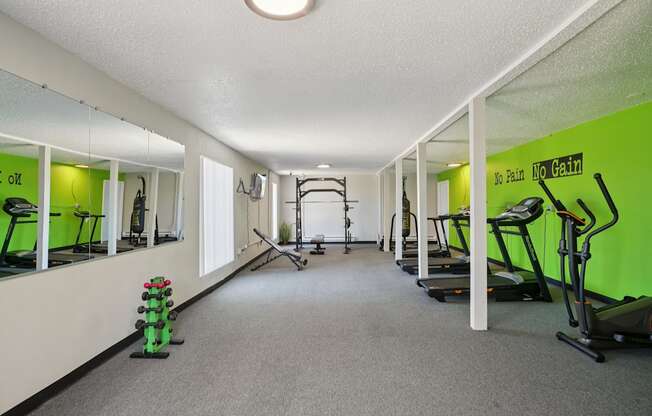 A gym with a green wall and a sign that says "No Pain, No Gain".