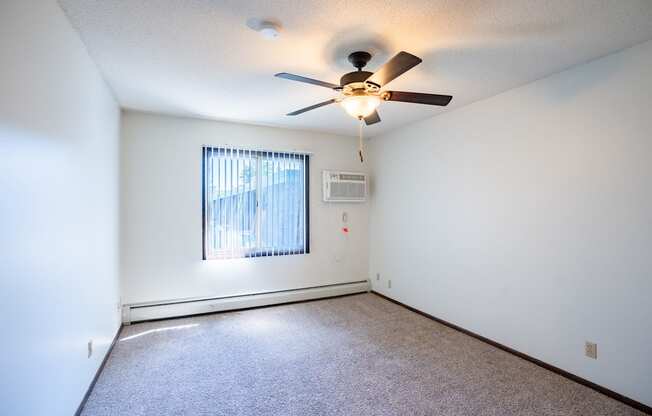 an empty living room with a ceiling fan and a window. Eagan, MN Glen Pond Apartments