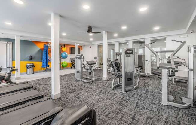 a gym with treadmills and other exercise equipment in a building with white ceilings