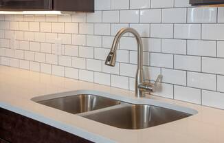 quartz countertops and tile backsplash and undercabinet lighting