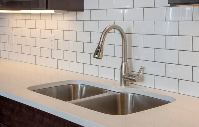 quartz countertops and tile backsplash and undercabinet lighting