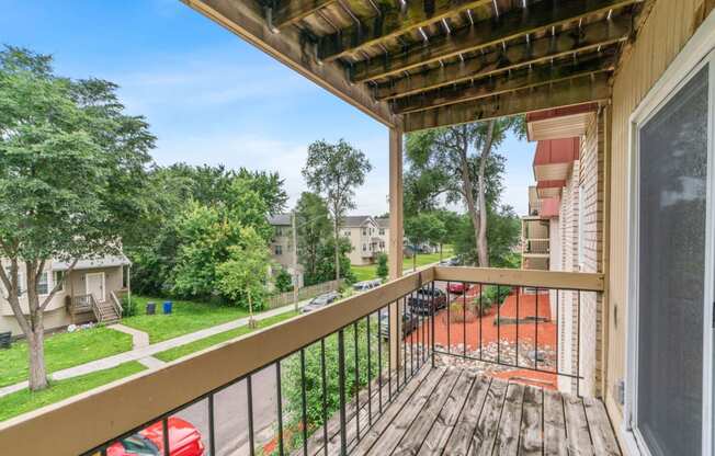 a balcony with a wooden railing and a view of a yard and trees