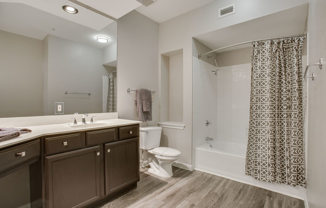 View of Bathroom with Plank-Wood Flooring, Garden Tub, and Oversized Mirror at Raveneaux Apartments