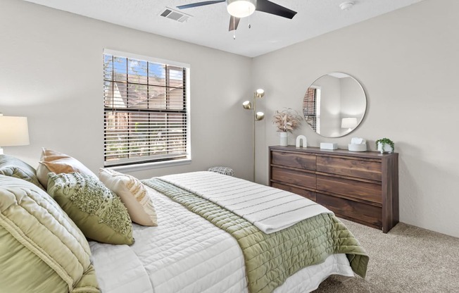 A bedroom with a large bed, a dresser, and a ceiling fan.