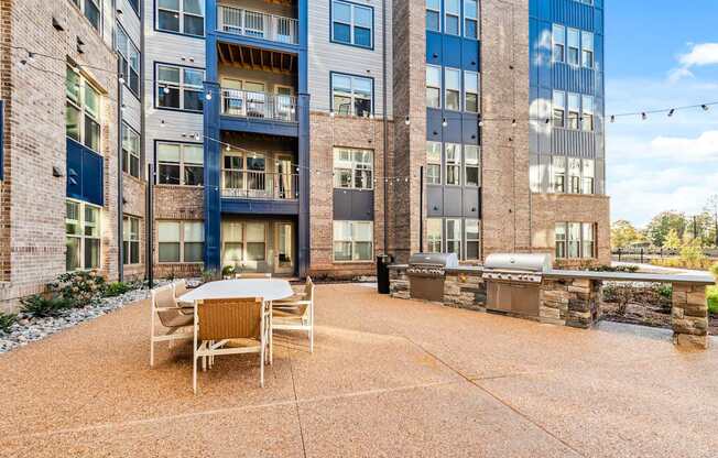 A patio area with a table and chairs in front of a multi-story building.