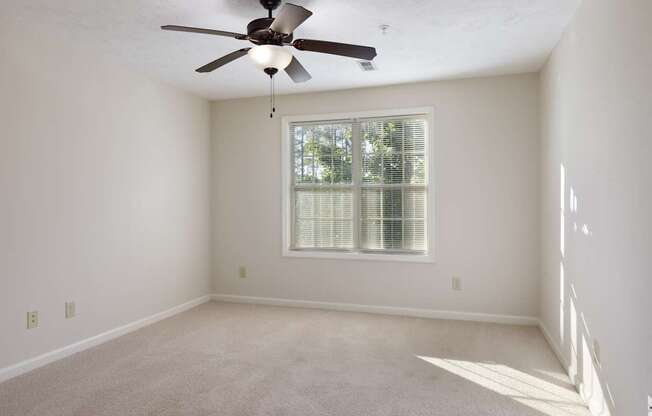 A room with a ceiling fan and a window with blinds.