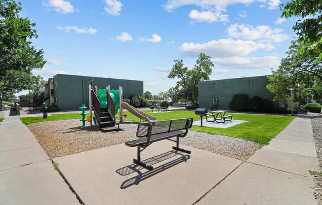 a park with a playground and benches in front of a building