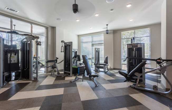 a fitness room with weights and cardio machines and a large window