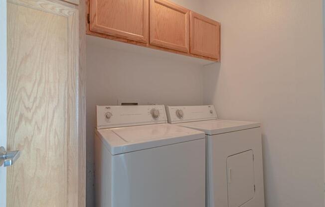 a washer and dryer in a room with wooden cabinets at Warner Center Townhomes, Canoga Park, CA