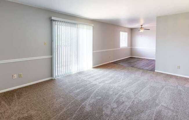 an empty living room with a window and a ceiling fan