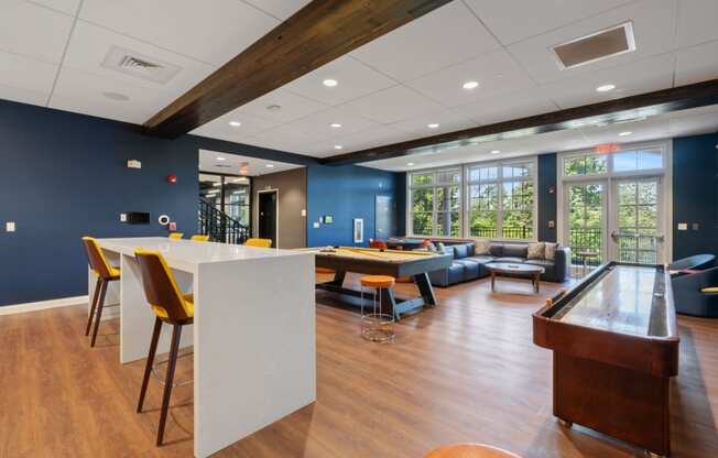 a communal room with a bar and a table with chairs and a pool table