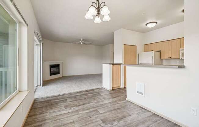 A spacious kitchen with a wooden floor and carpeted living room with a fireplace at The Madison Apartments in Olympia, WA