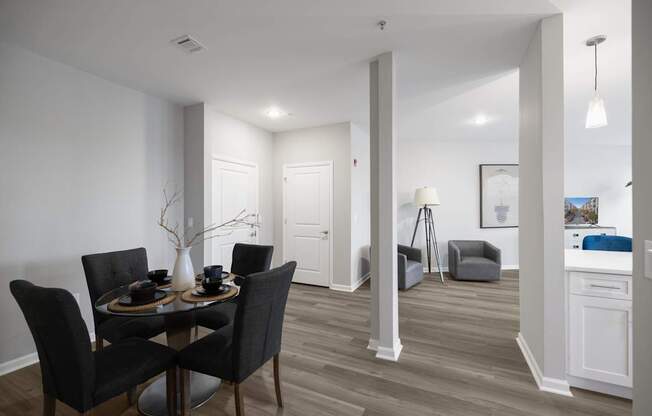 A dining room with a table set for two and a kitchen area in the background at Harbor Pointe Apartments, Bayonne 07002