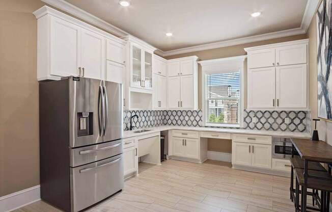 A kitchen with a stainless steel refrigerator and white cabinets.