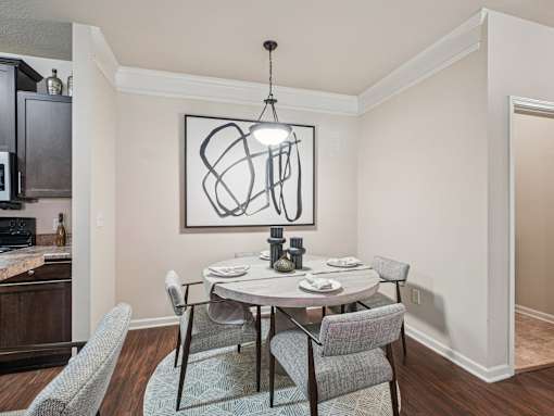 A dining room with a table set for two and a modern art piece on the wall.