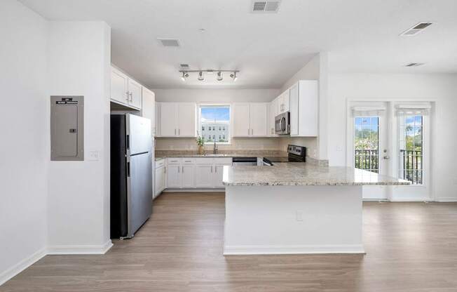 A kitchen with white cabinets and a black fridge.