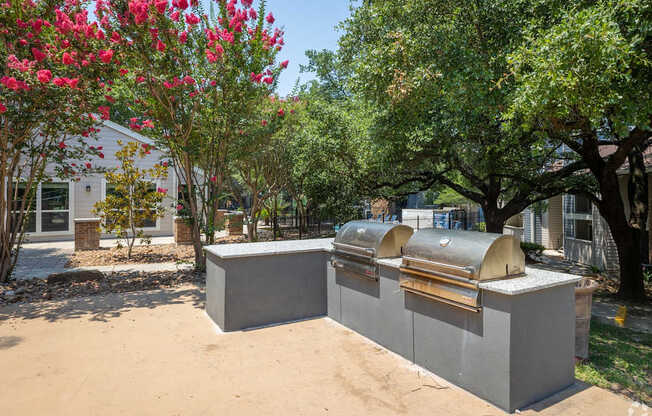 A concrete structure with a metal roof is surrounded by trees and bushes.