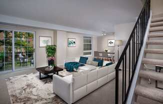 a living room with a white couch and a staircase
