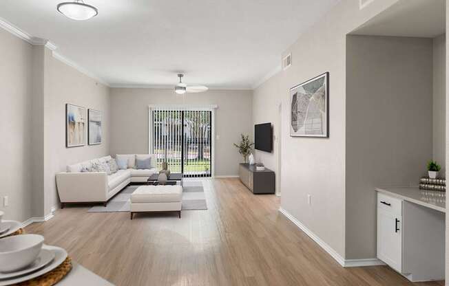 Bright living room with wood-style flooring, crown molding, and sliding glass door to patio.