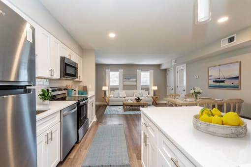 an open kitchen and living room with white cabinets and stainless steel appliances