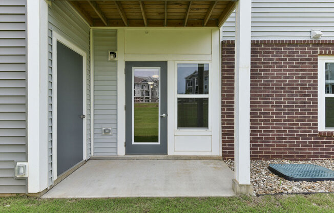 a front porch with a gray door and a red brick wallat Chase Creek Apartment Homes, Alabama