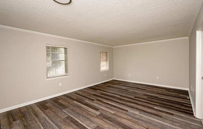 A room with wooden flooring and a window with blinds.