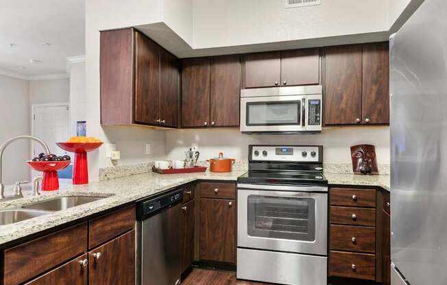 A modern kitchen with dark wood cabinets and stainless steel appliances.