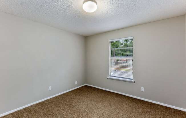 an empty bedroom with a window and a cork floor