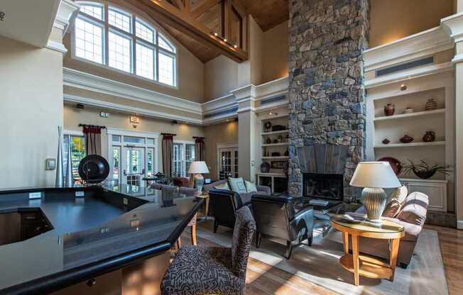 a large living room with a large stone fireplace and a pool table