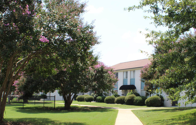 neatly kept sidewalk with mature trees, and neat apartment buildings  at Huntsville Landing Apartments, Alabama