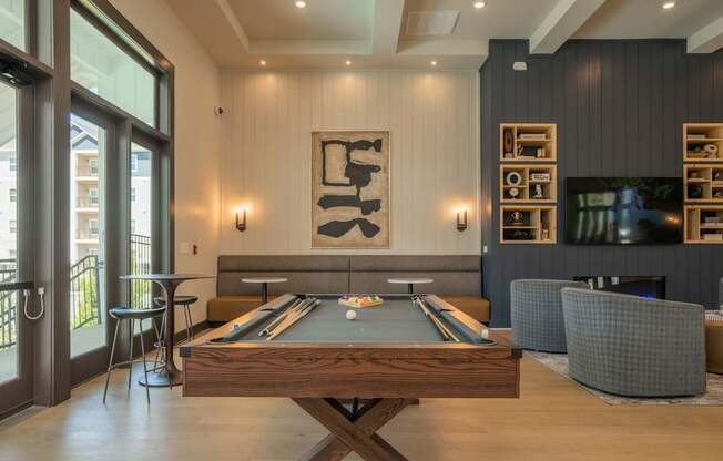 A pool table is in the middle of a room with a fireplace and a TV at The Ashton at East Park Apartments, Georgia, 30144