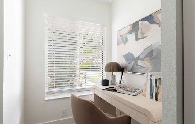 A brown chair is in front of a desk with a lamp and books on it.