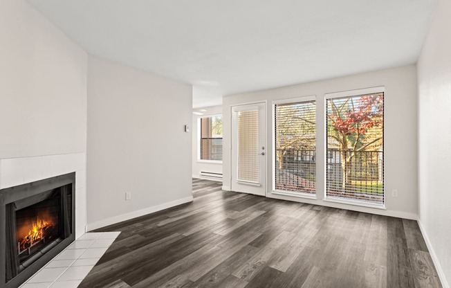 A room with a fireplace and a view of a tree outside.