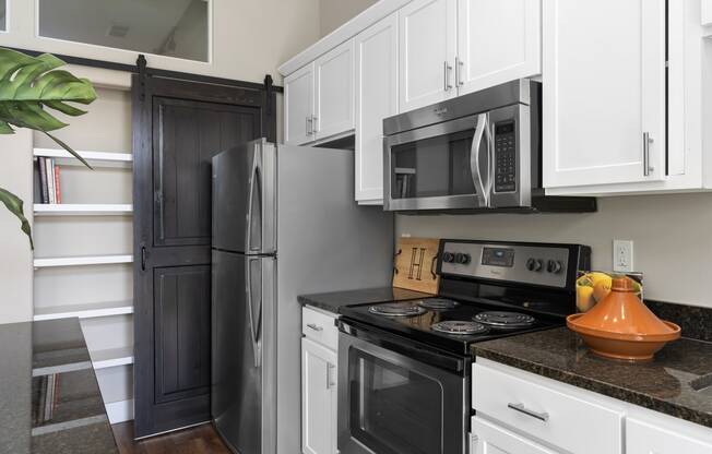 a kitchen with black appliances and white cabinets and a refrigerator at Hayden Lofts, Dublin, Ohio