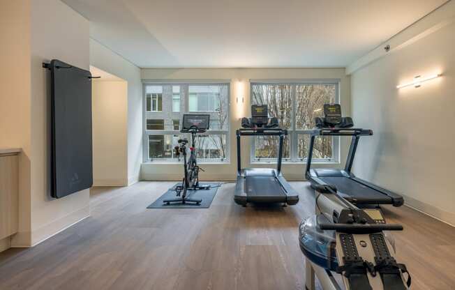 a gym with treadmills and weights and a tv