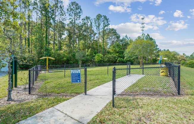 A sign is on a fence in front of a grassy area.