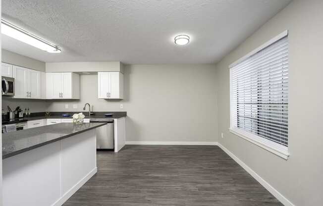 a kitchen with white cabinets and a large window