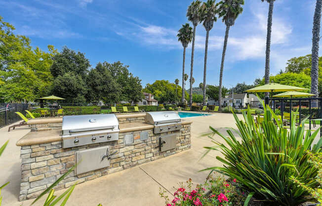 A backyard with a stone wall and a grill.