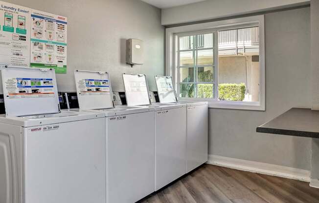 A laundry room with a row of washing machines and a signboard.