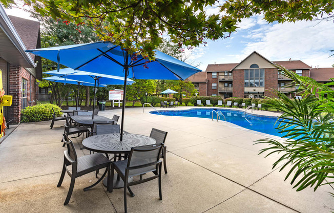 outdoor dining tables with blue umbrellas next to The Addison at Southfield swimming pool