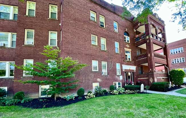 A red brick building with a tree in front.