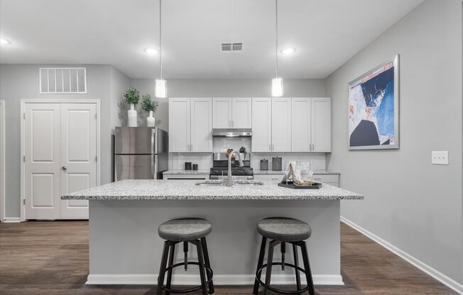 an island with two stools in front of a kitchen