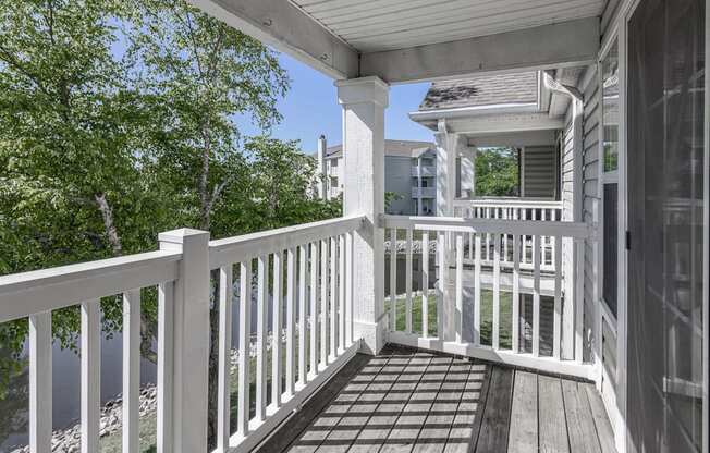 a porch with a white railing and a house in the background