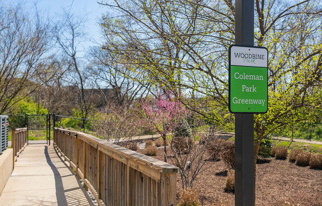 a wooden bridge in a park with a sign that reads