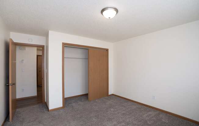 an empty room with a closet and a door to a bathroom. Fargo, ND Country Club Apartments