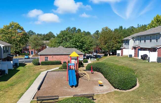 A playground with a blue slide and a yellow ball is in the foreground of a residential area.