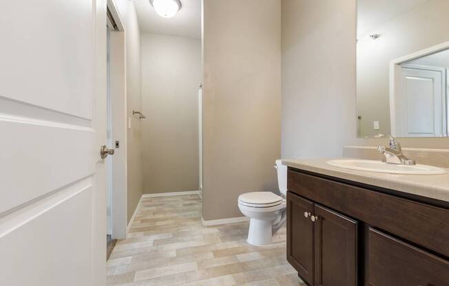 A bathroom with a toilet, sink, and mirror.