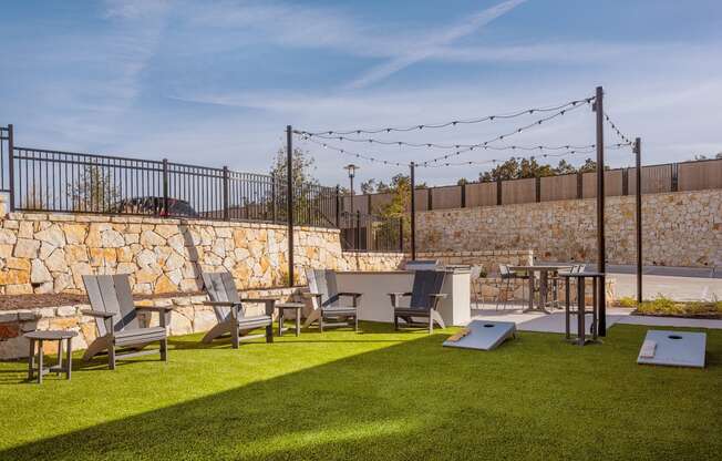 a backyard with lawn chairs and tables and a stone wall