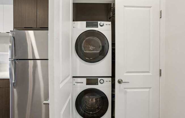 A white door is open to reveal a washing machine and dryer.