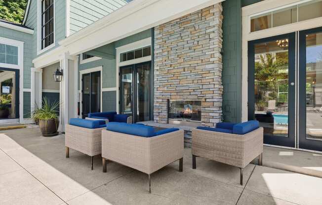 a patio with couches and a fireplace in front of a building